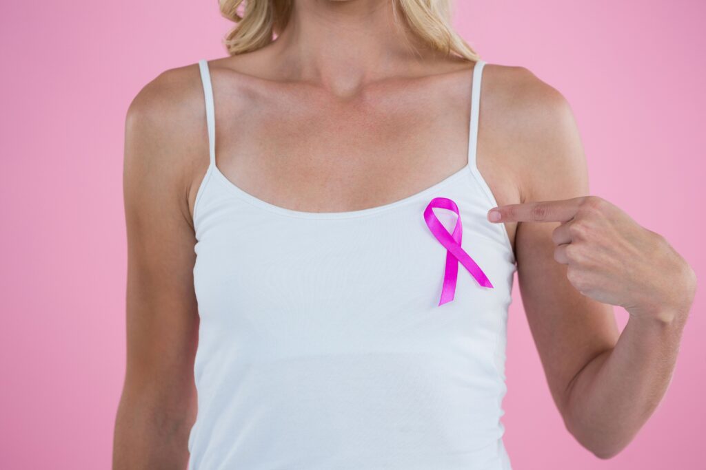 Woman points at Breast Cancer Awareness ribbon